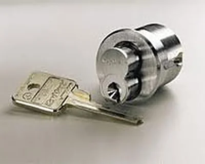 Chrome cylinder lock lying beside its key