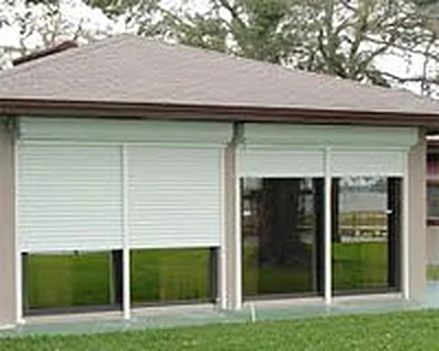 Roller shutters part-lowered over the windows of a single-storey building